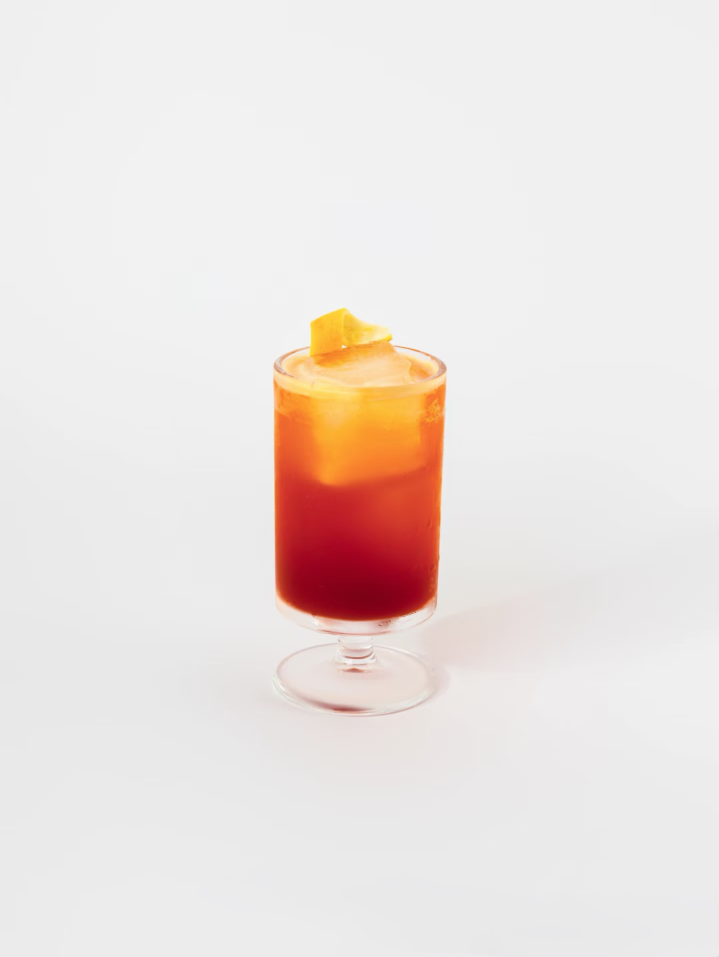 鸡尾酒白底产品图，玻璃杯装渐变红橙色饮品顶部有橙皮