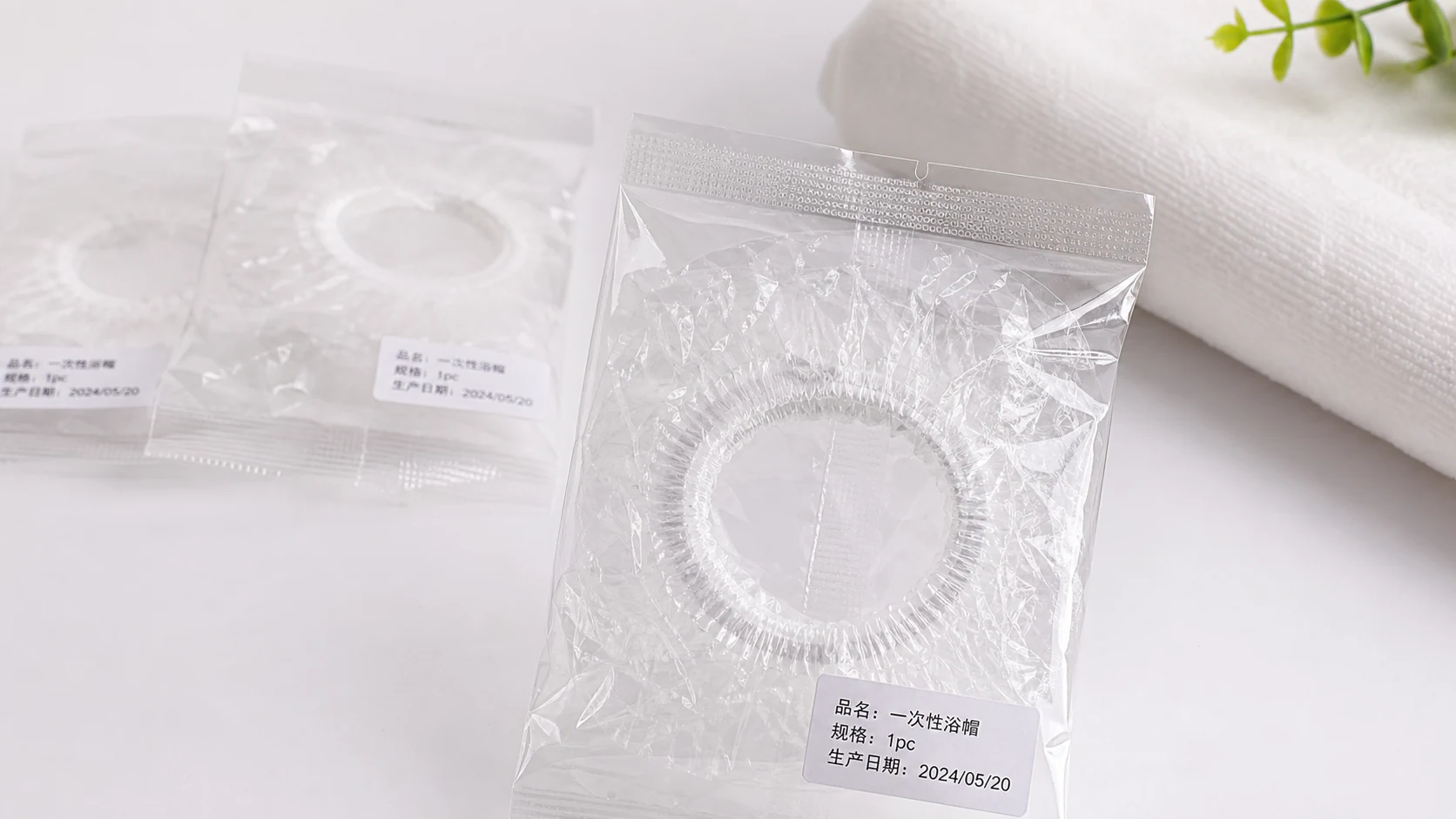 酒店一次性浴帽独立包装放在白色工作台上，封口松紧圈和日期码清楚可见